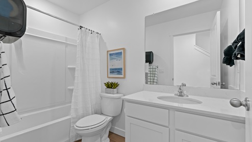 Full-sized bathroom with modern light cabinets and white shower surround.