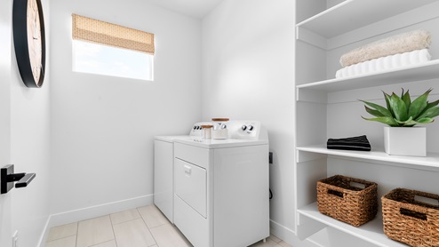 Laundry room with window and shelving storage.