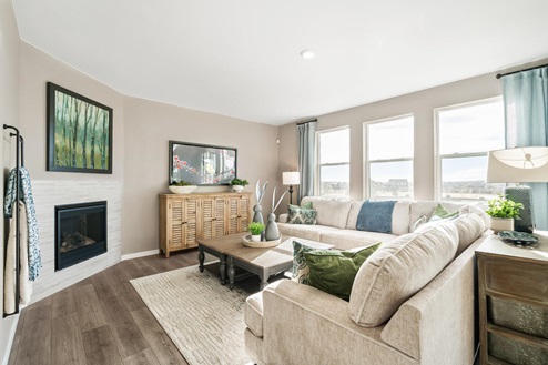 View of open living room with electric fireplace, laminate hardwood flooring and large windows