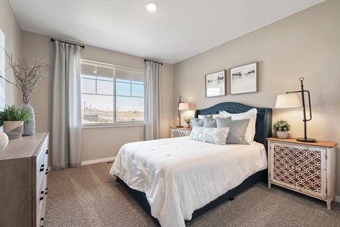 Guest bedroom with queen size bed, night stands, dresser, and large window letting in natural light