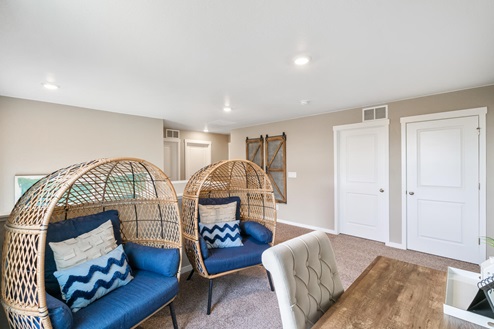 Flex room converted into home office with two padded wicker seats and blue accents