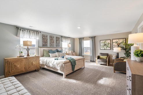 Main bedroom with three windows, fully furnished with bed, seating, nightstands, and lamps