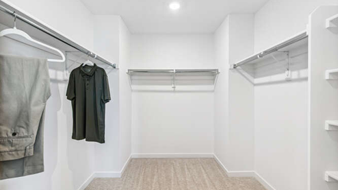 Furnished Muirfield model home walk-in closet with built-in shelves in foreground