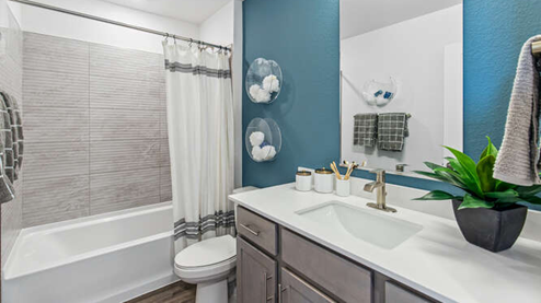Secondary bathroom in furnished Muirfield model home displaying a quartz countertop vanity with dual undermount sink and tub/shower combo