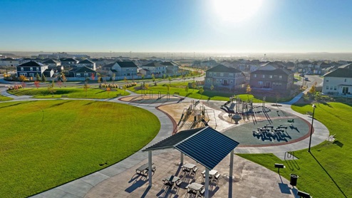 Closeup of swingset, plaground amenities, bikerack, and gazebo beside cicular path equipped with picnic tables and grill.