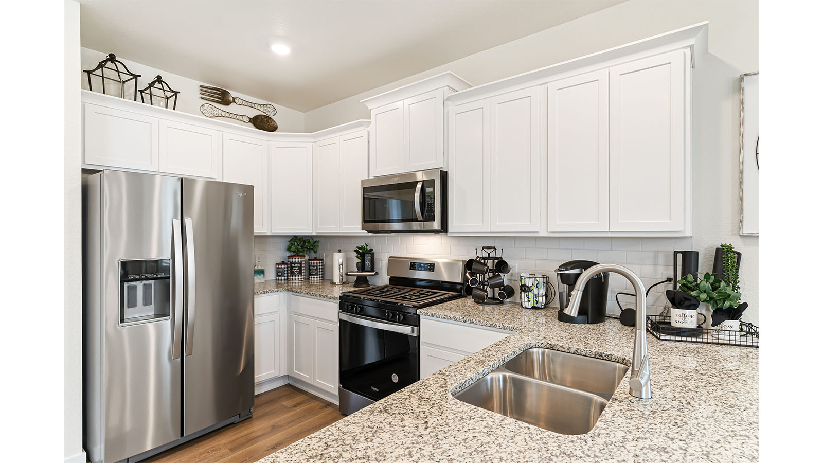 Alternate view of Alamosa model kitchen showing oven, stovetop and microwave, plus expansive countertops and undermount sink