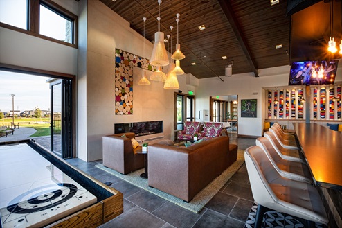 Club house for Harmony by D.R. Horton featuring tabletop shuffle board, fireplace seating area and bar