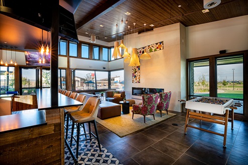 Alernate view inside Harmony club house showcasing bar, fireplace and foosball table