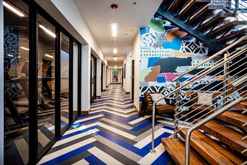 Lower floor landing of Harmony community club house featuring colorful wall and floor leading to gym
