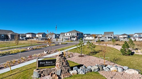 Pine Ridge at Crystal Valley community monument sign with sidewalk and gravel pathway nearby and new homes in background