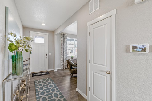 Model home at Crystal Valley Pine Ridge interior entry, paneled front door with window, home office and smart home IQ panel