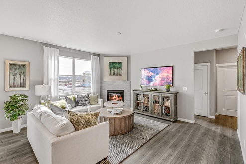 Pine Ridge at Crystal Valley model home living room with corner fireplace, large operable windows and laminate hardwoods