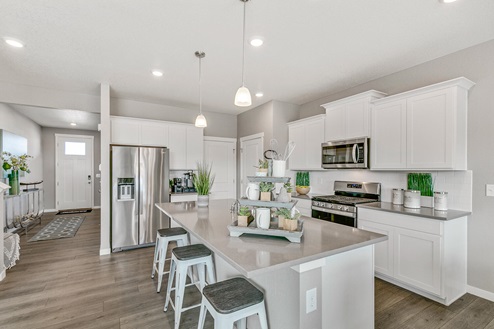 Contemporary model home kitchen at Pine Ridge in Crystal Valley showcasing gleaming quartz countertops and white cabinetry