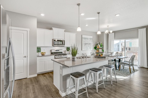 Alternate view of Pine Ridge model kitchen with island, pendant lights, stainless steel appliances and full height backsplash