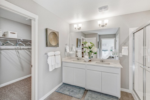 Private bathroom in Crystal Valley model home with double undermount sinks, large step-in shower and spacious storage closet