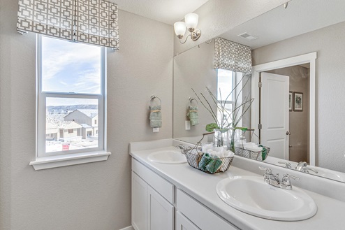 Henley model home at Pine Ridge hallway bathroom double sink vanity with bright window and privacy door to tub shower area
