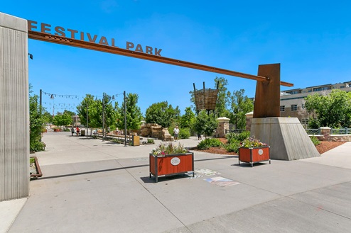 Modern iron entry sign to Festival Park in Castle Rock Colorado displaying festive overhead lighting and ample seating