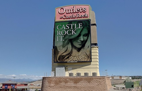 A large LED advertising sign, on the entry monument sign for the expansive Outlets shopping center at Castle Rock Colorado