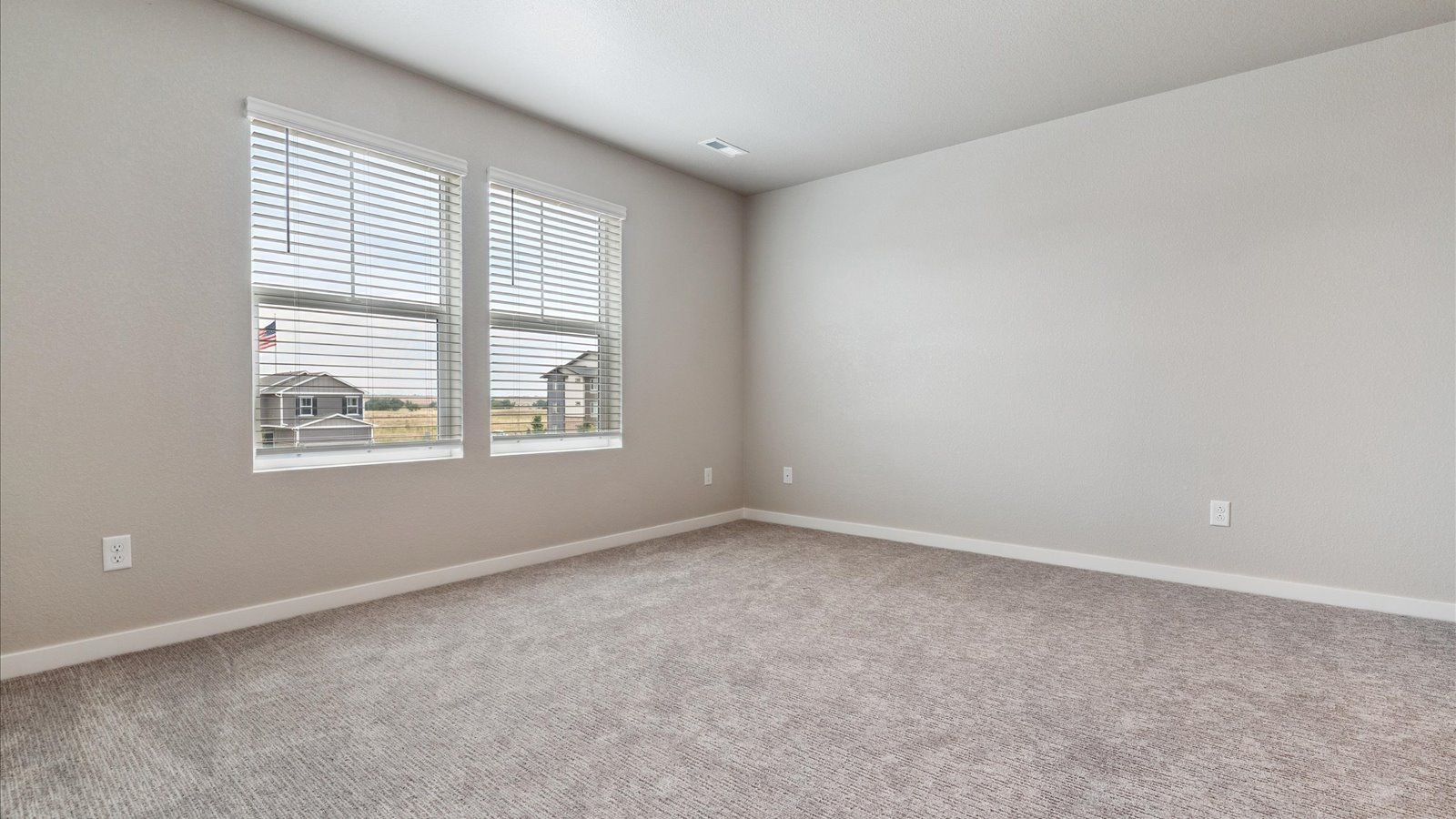 Spacious primary bedroom with large windows in new D.R. Horton home in Watkins, Colorado