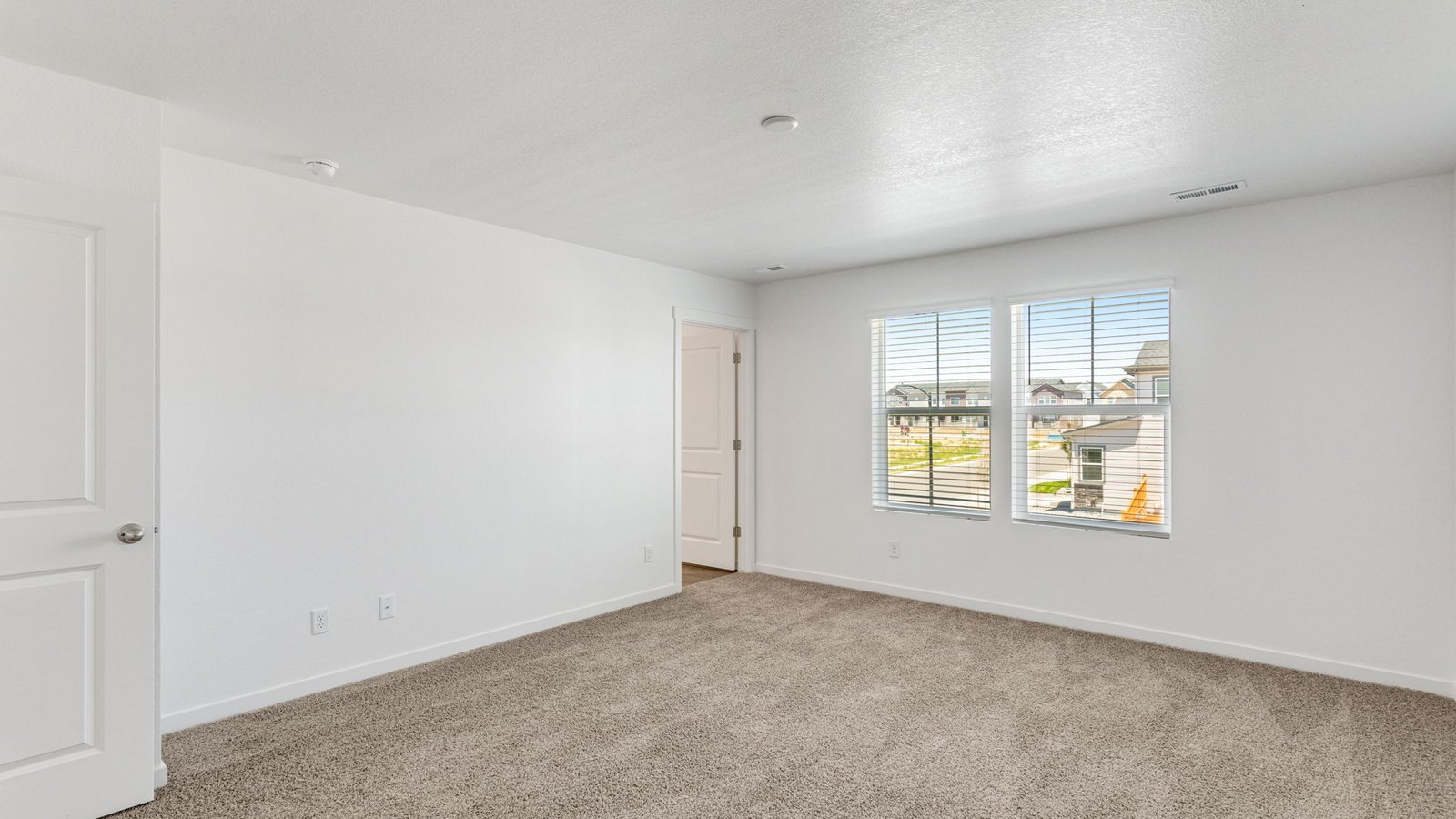 Spacious primary bedroom with natural light in new home in Watkins Colorado