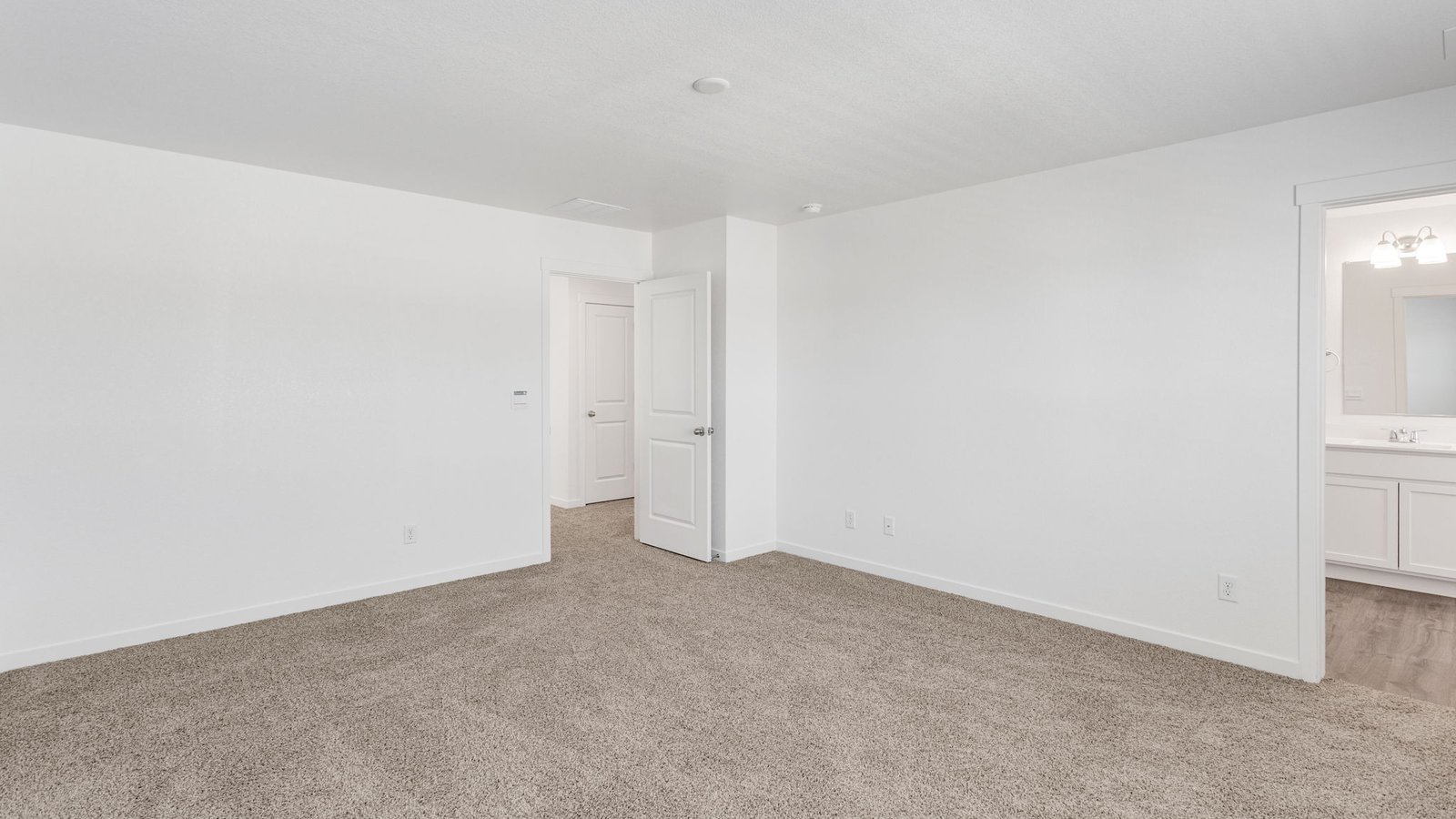 Spacious primary bedroom with attached bathroom in new home in Watkins, Colorado