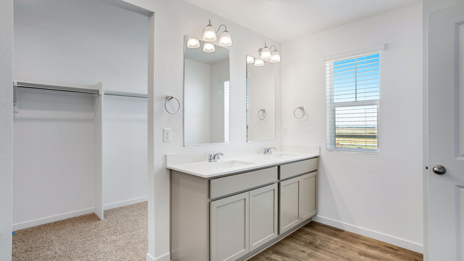 Attached private primary bathroom with dual vanity sinks in new home community Sky Ranch