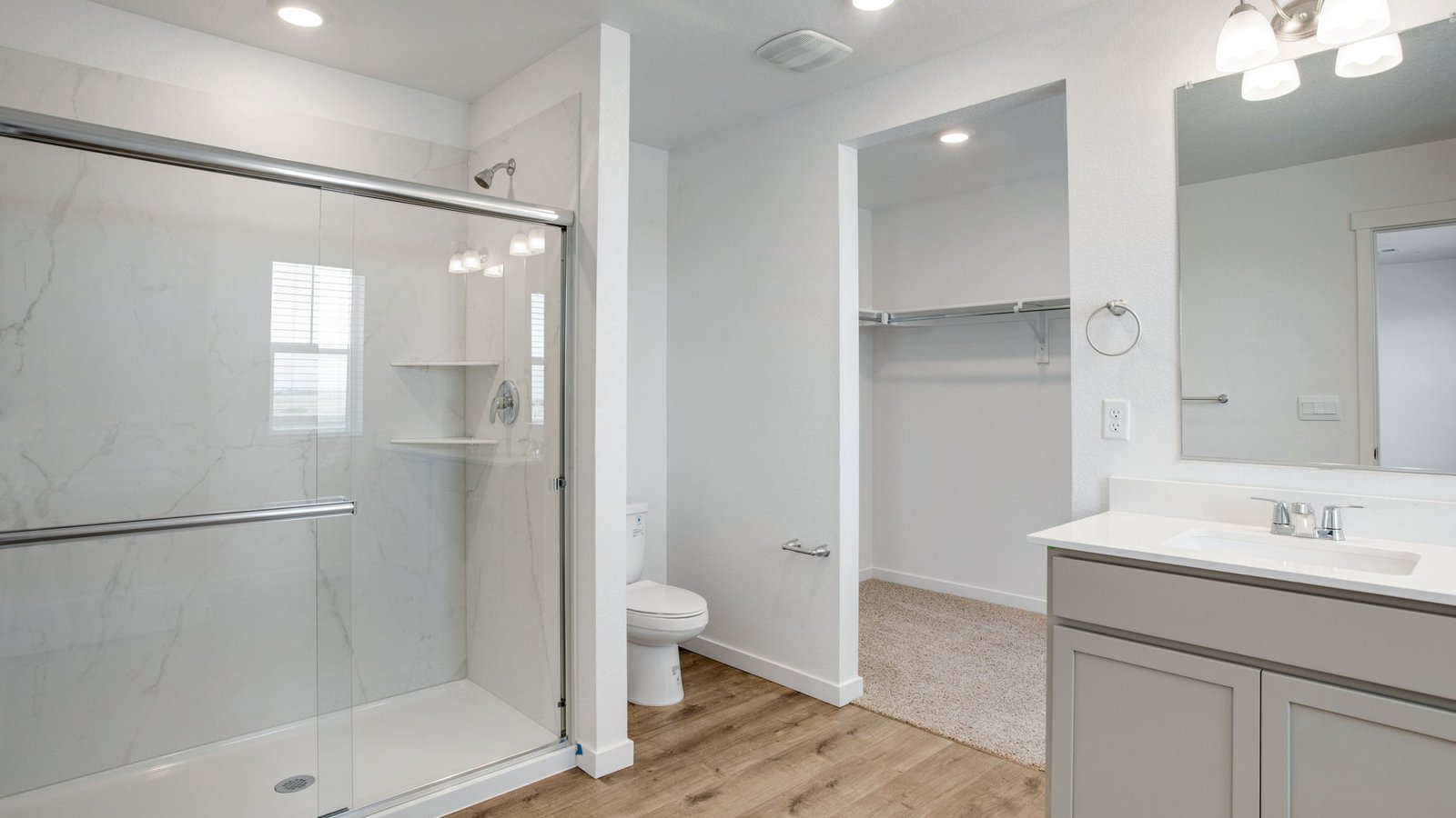 Attached private primary bathroom with dual vanity sinks in new home community Sky Ranch
