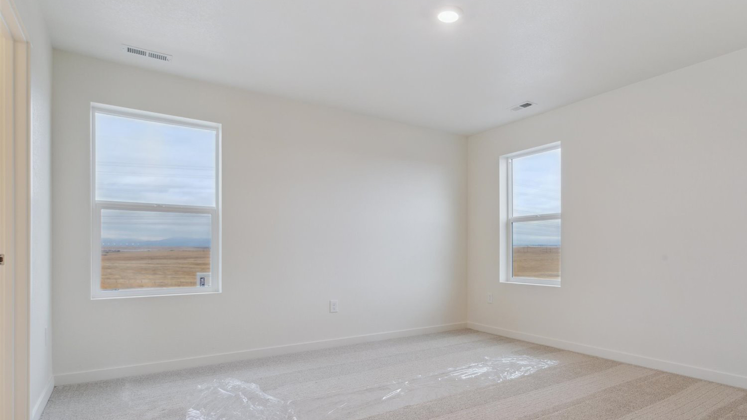 Primary bedroom with large windows in new home community Sky Ranch