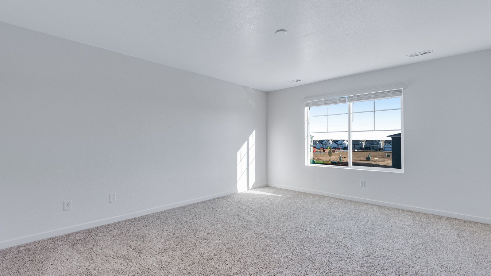 Spacious primary bedroom with large windows in new home at Sky Ranch Community