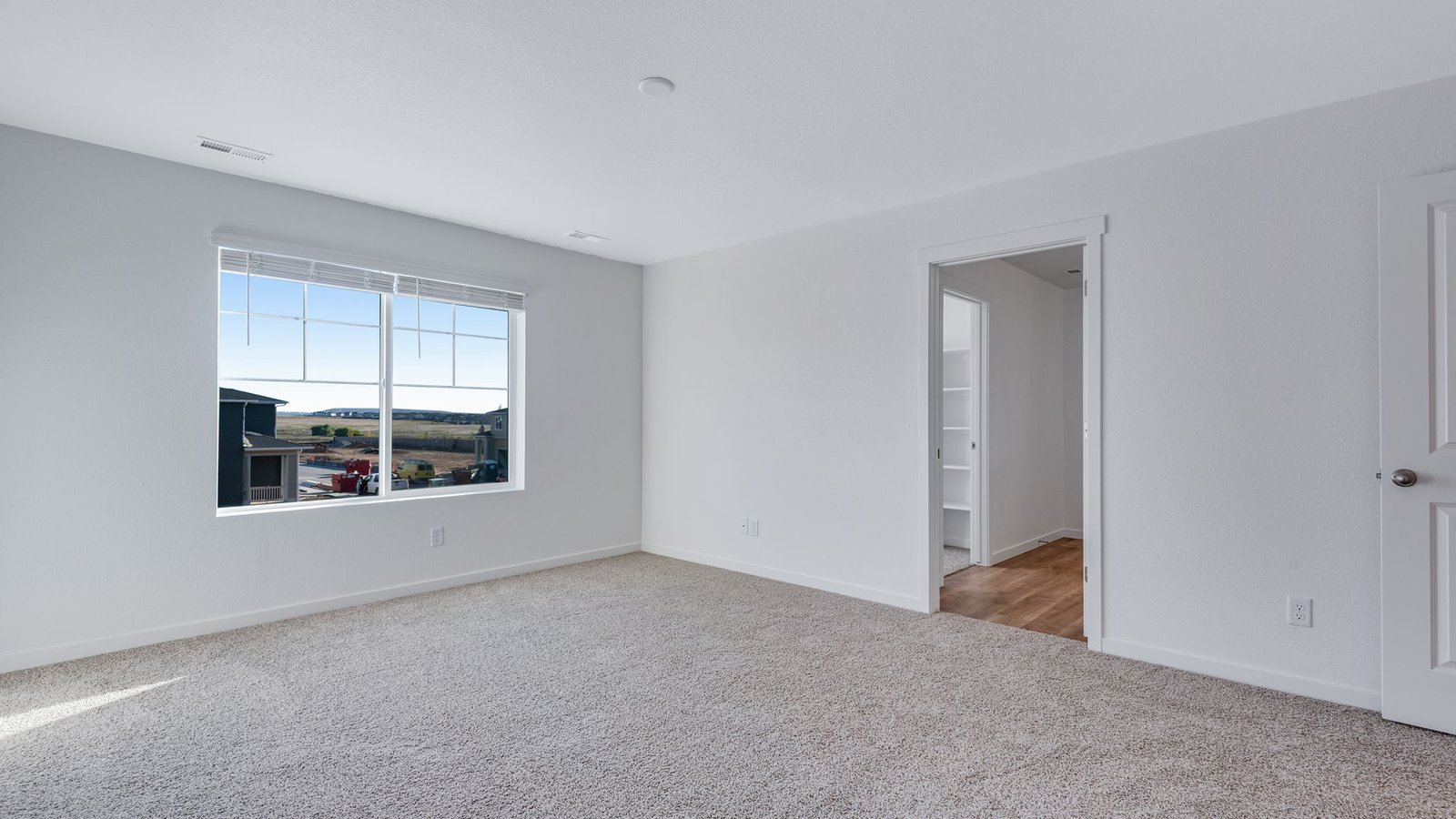 Spacious primary bedroom with large windows in new home at Sky Ranch Community