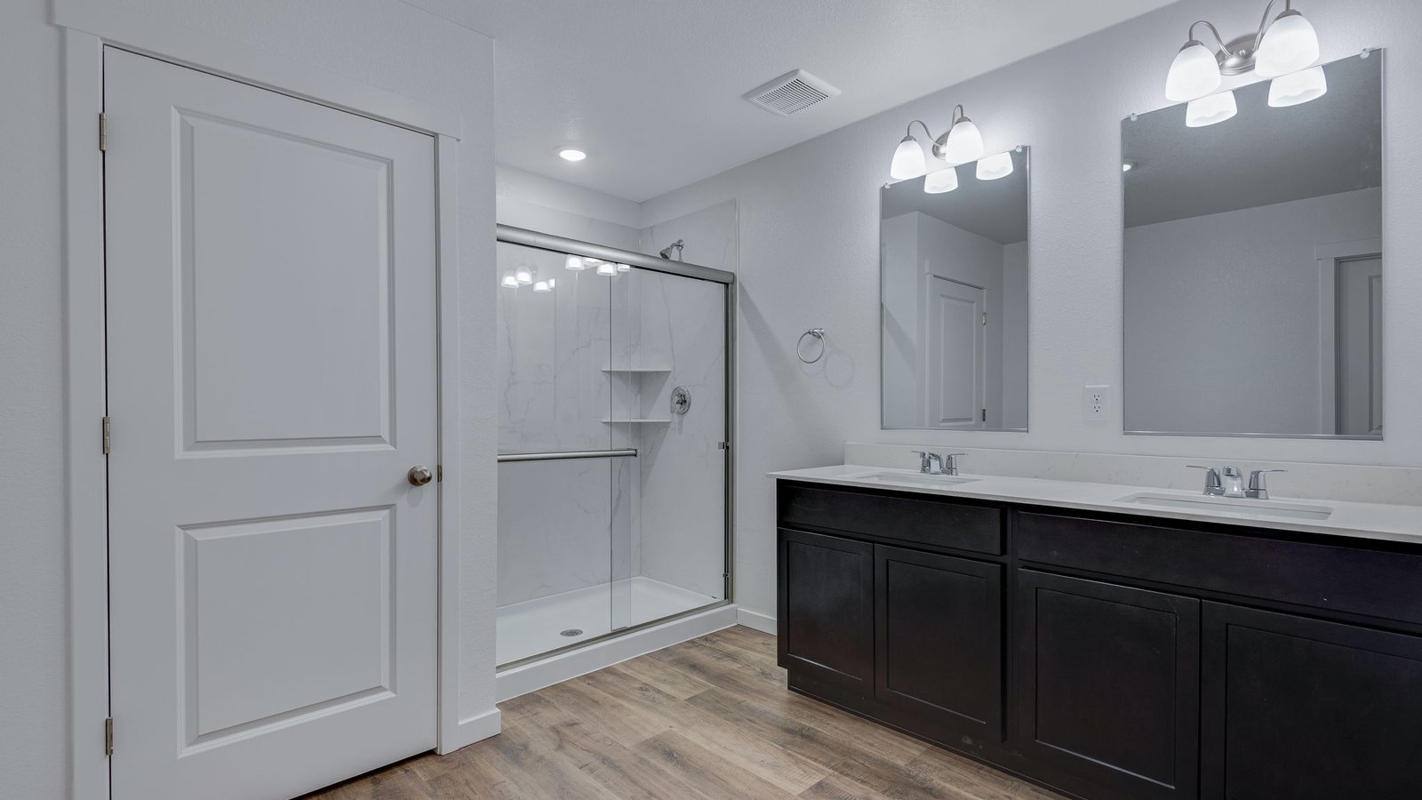 Attached private primary bathroom with dual vanity sinks in new home in Watkins Colorado