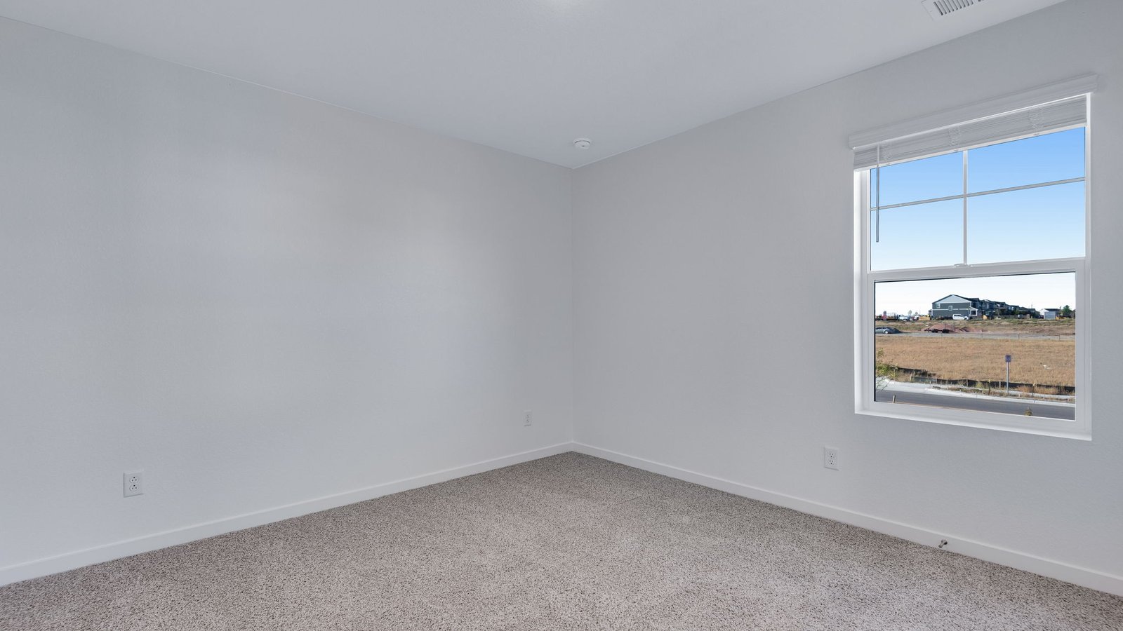 Secondary bedroom with large window in new home at Sky Ranch