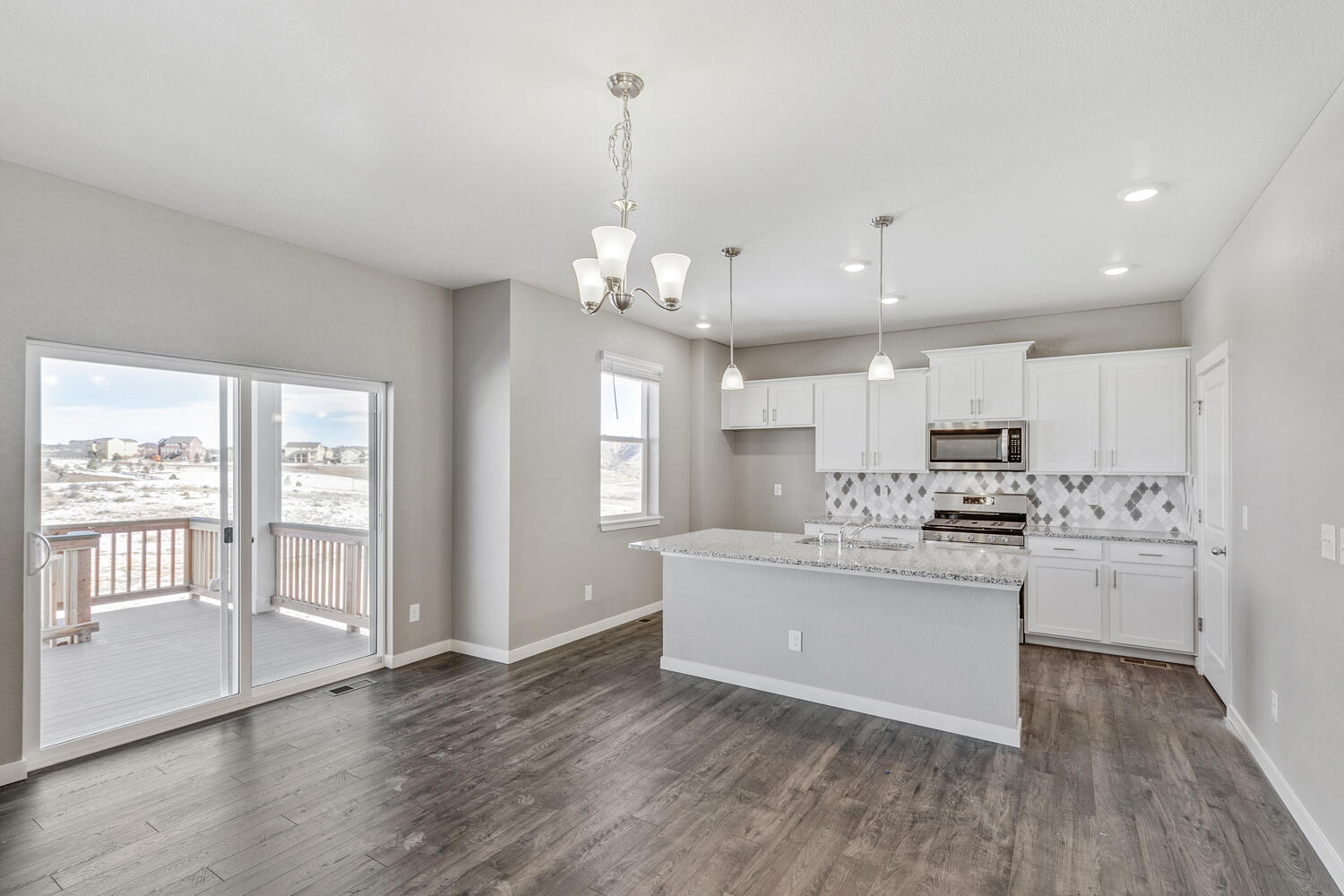 Dining nook with 3-light chandelier with sliding glass door and kitchen in background