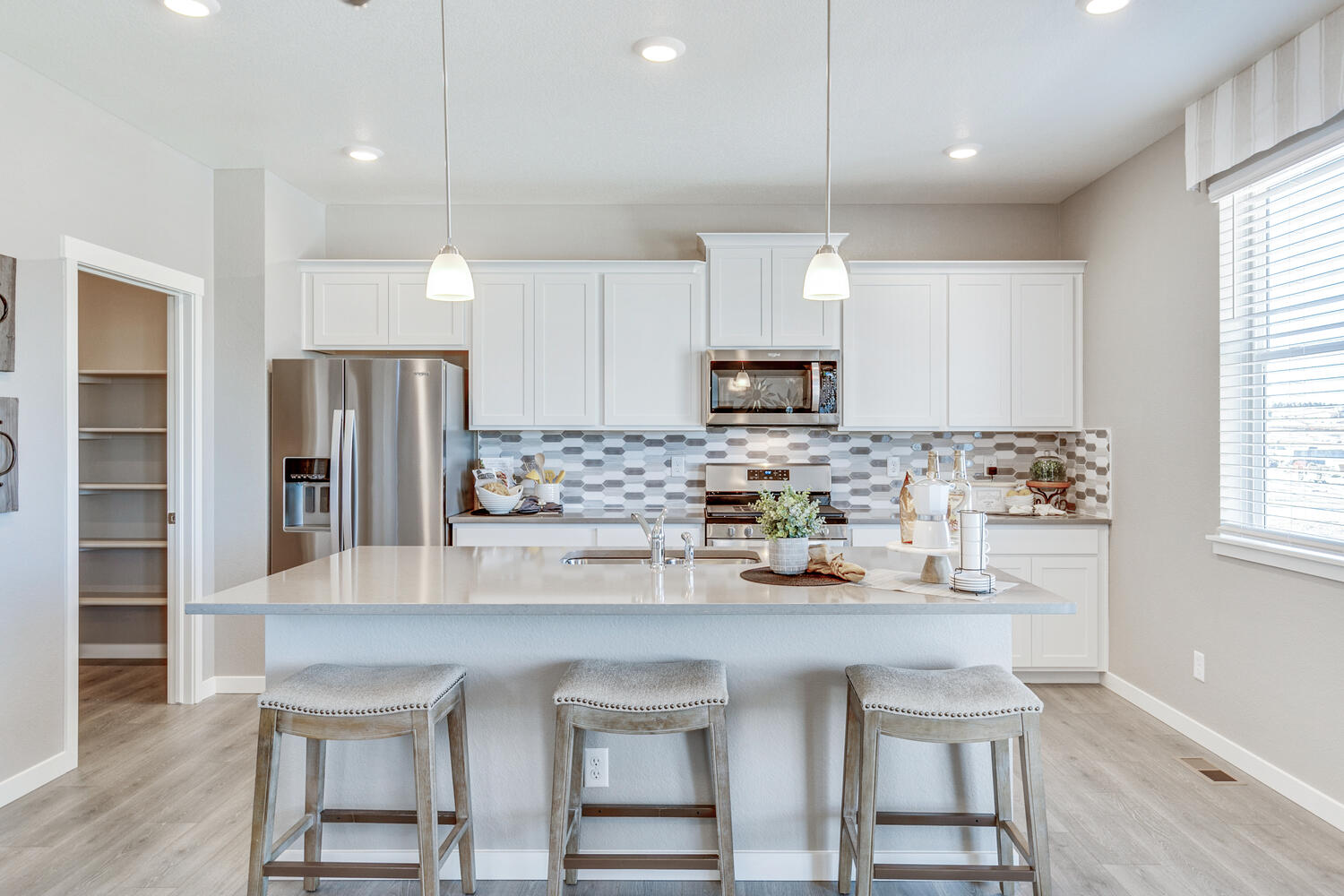 View of kitchen with white cabinetry, stainless steel appliances, island and walk-in pantry