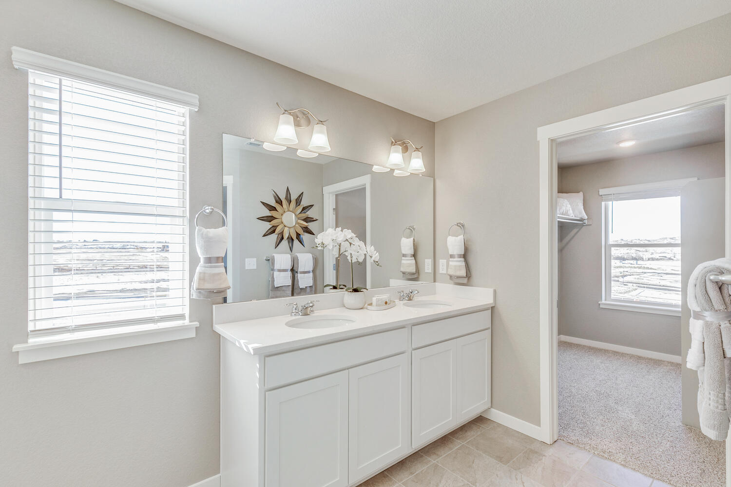 Bright view of private bathroom and walk-in closet showing windows in both