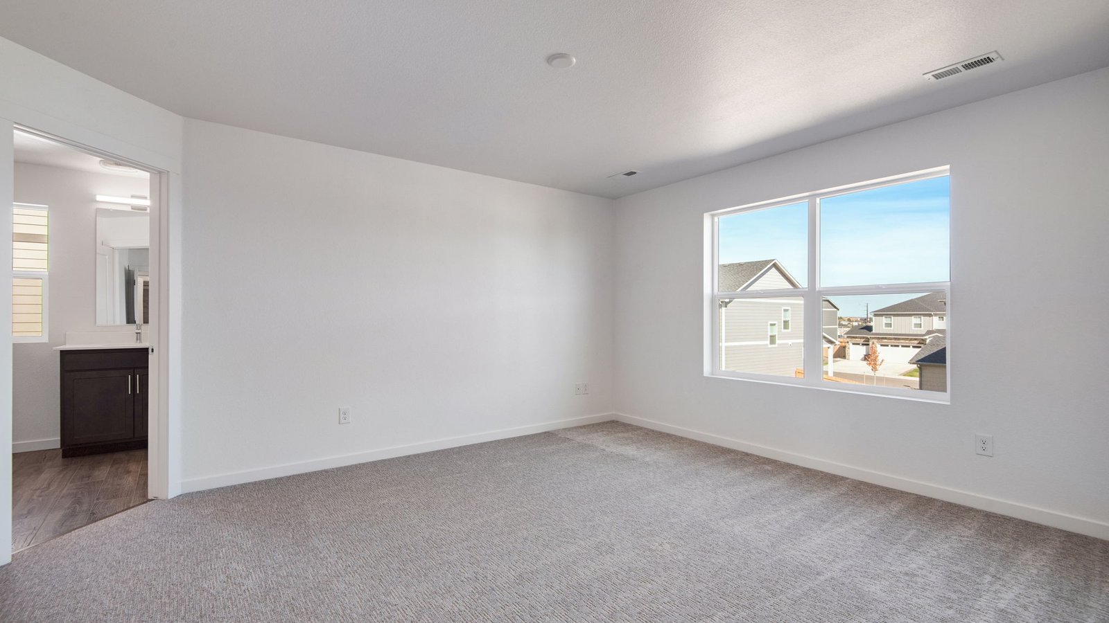 Spacious primary bedroom with large windows in new home community in Parker Colorado