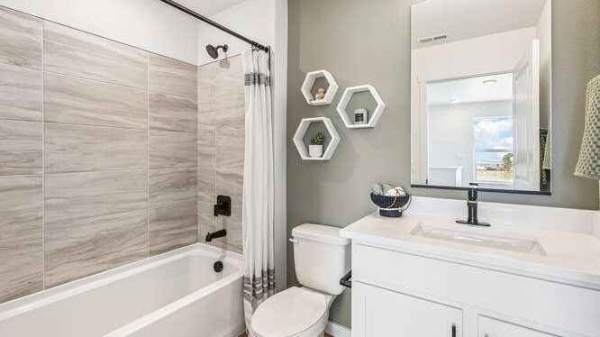 Hallway bathroom in Melbourne model home displaying dark vanity cabinet with undermount sink and tub shower combo