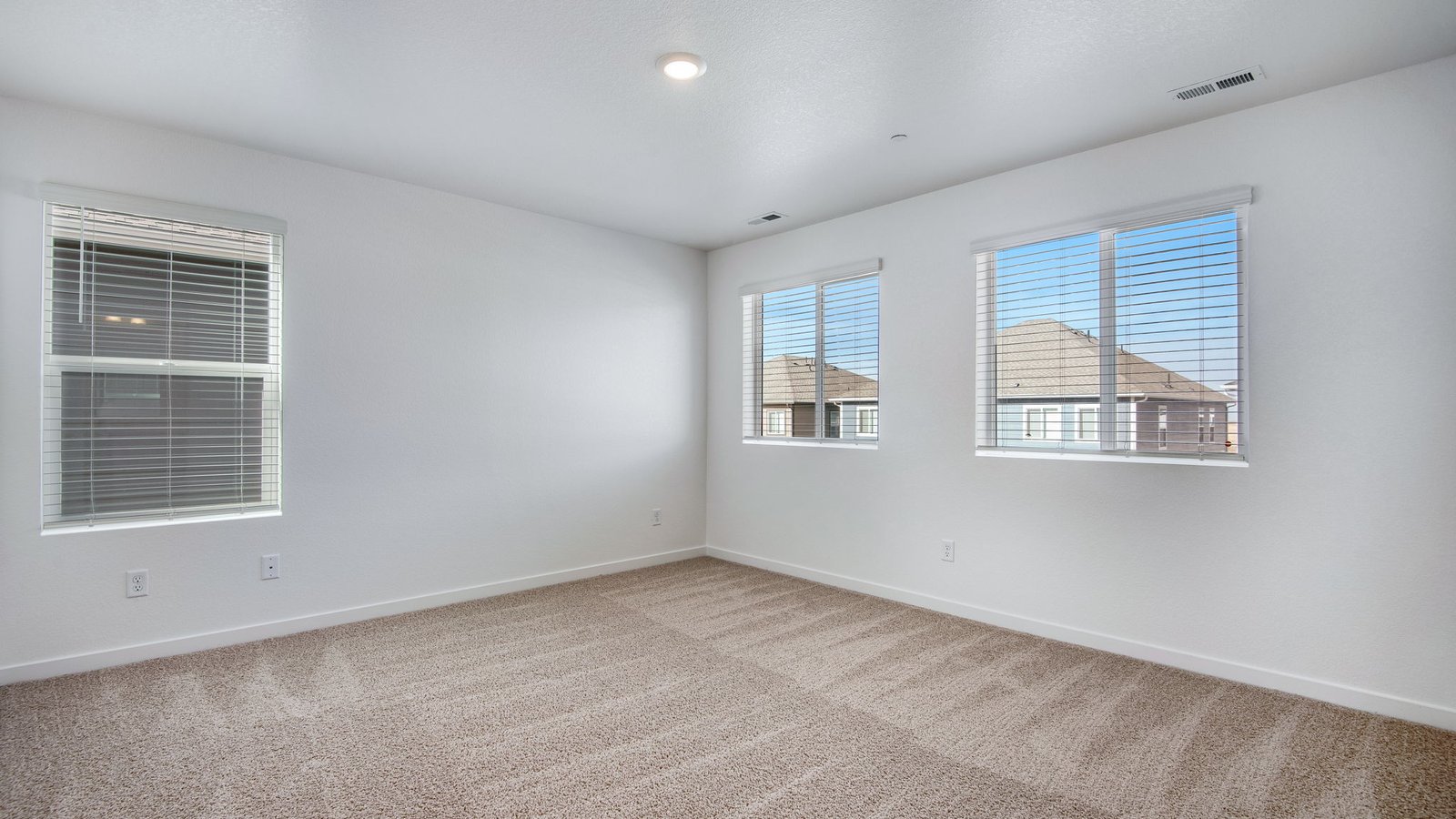 Spacious primary bedroom with large windows in new home community in Commerce City