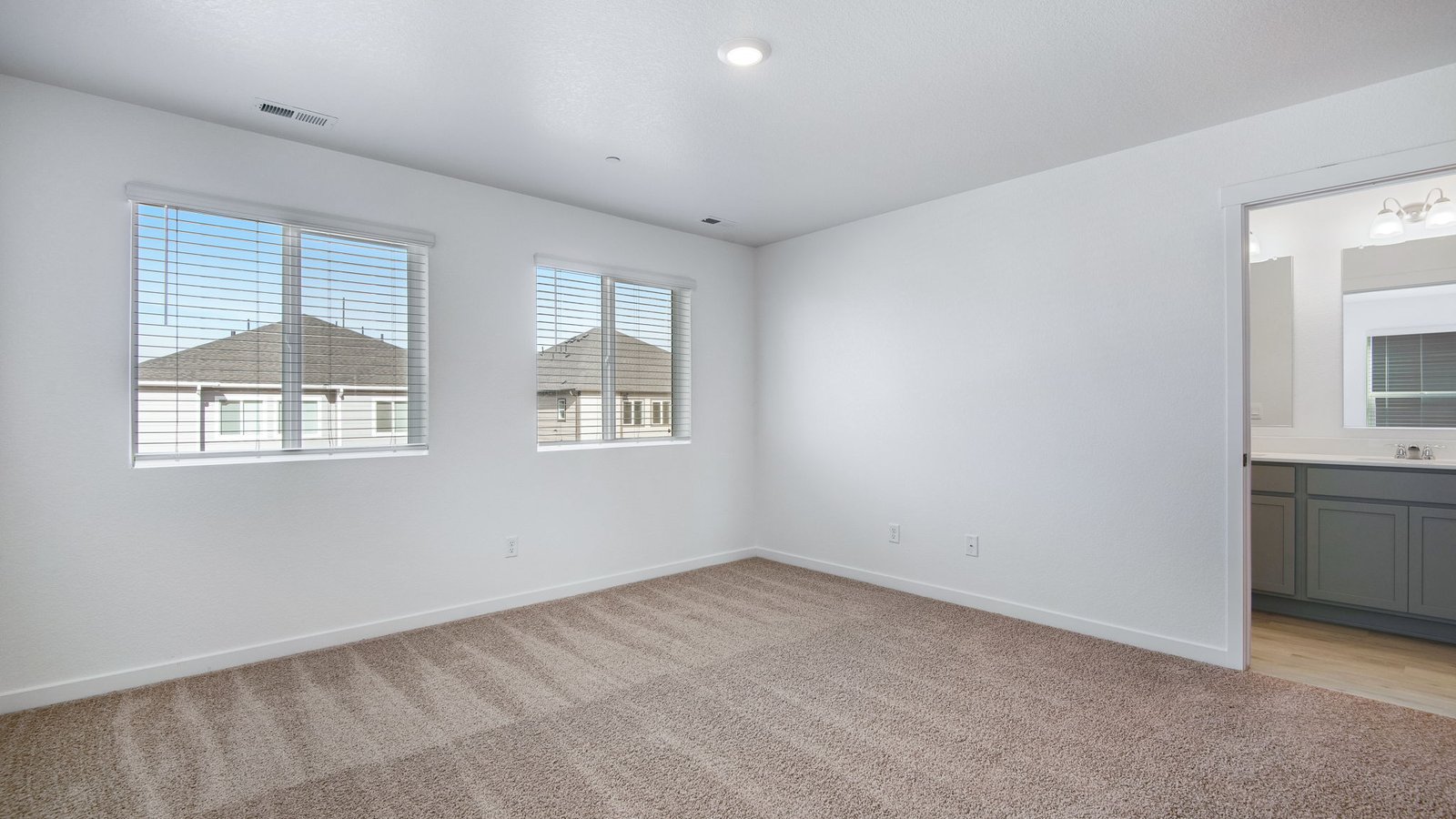 Spacious primary bedroom with large windows in new home community in Commerce City