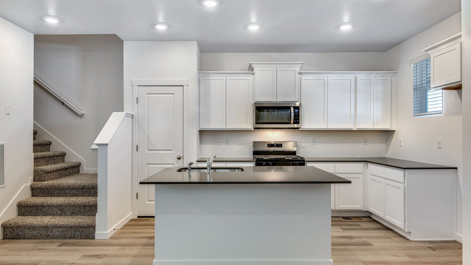 Bright kitchen in the Muirfield floor plan at Settlers Crossing featuring white cabinets, modern finishes, and natural light.