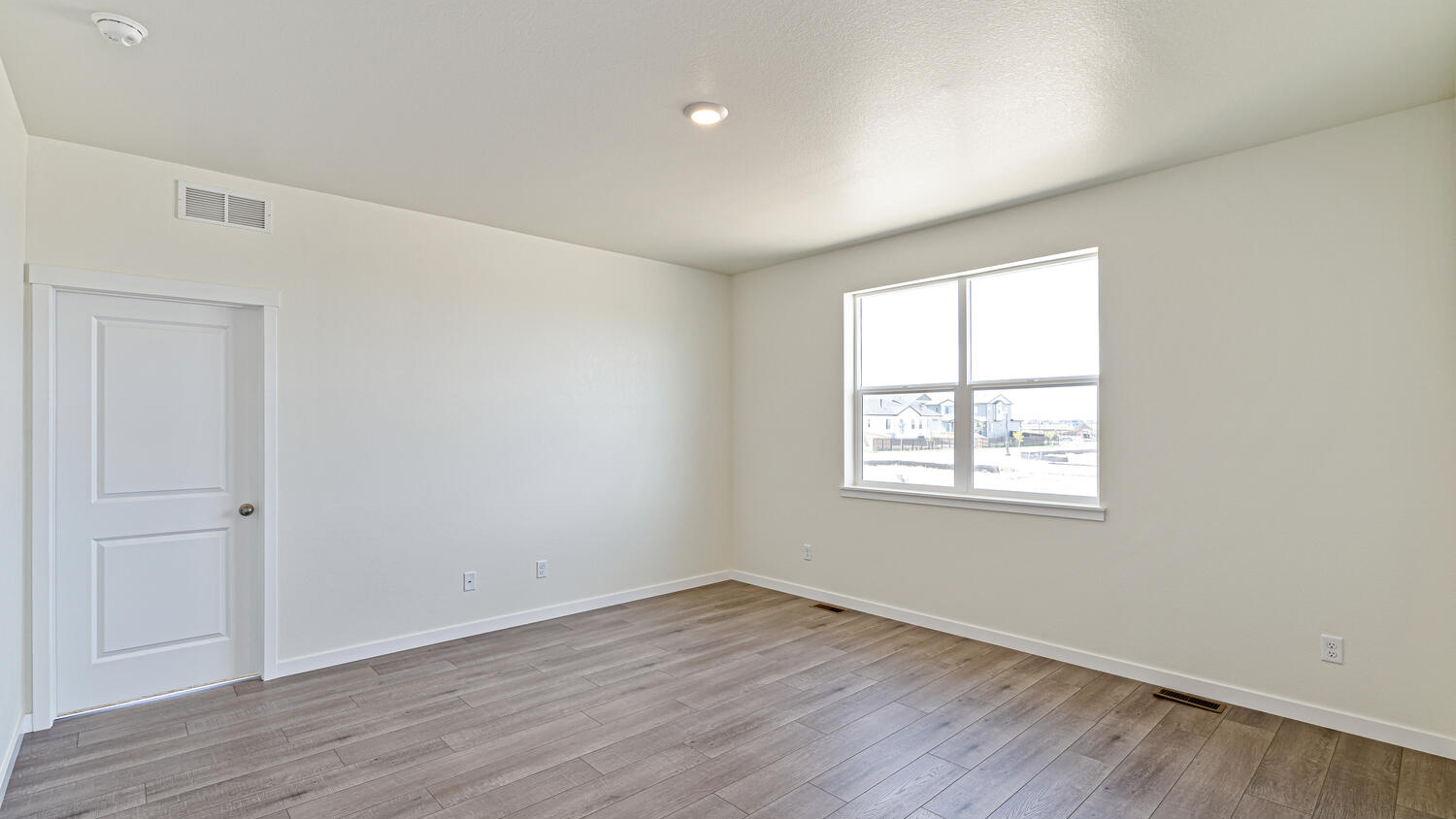 Alternative perspective of great room with ample natural lighting and hardwood flooring, and door to primary bedroom
