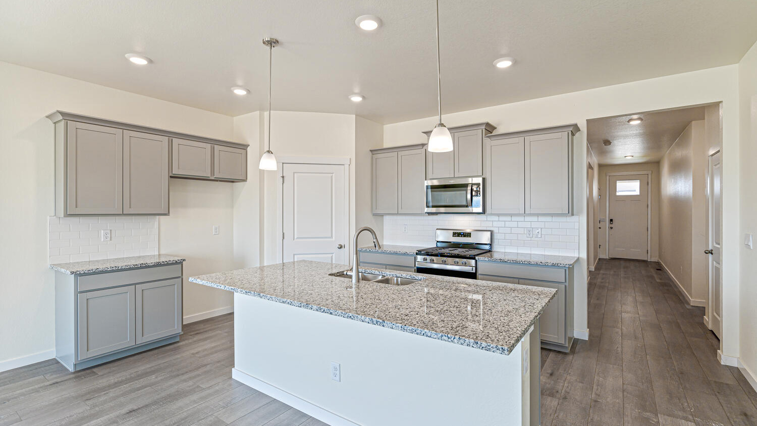 Angle view of kitchen showing premium cabinetry, corner pantry, and spacious center island with built-in sink