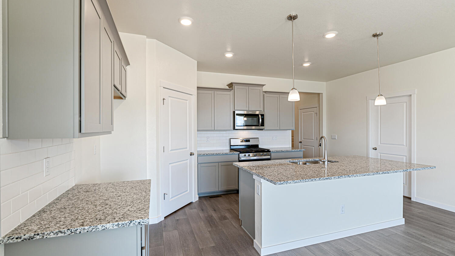 View of kitchen granite countertops, premium cabinetry, pantry, stainless steel appliances, and mechanical room door