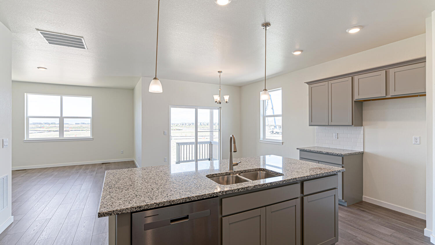 Behind kitchen island view of great room and dining nook with sliding patio door