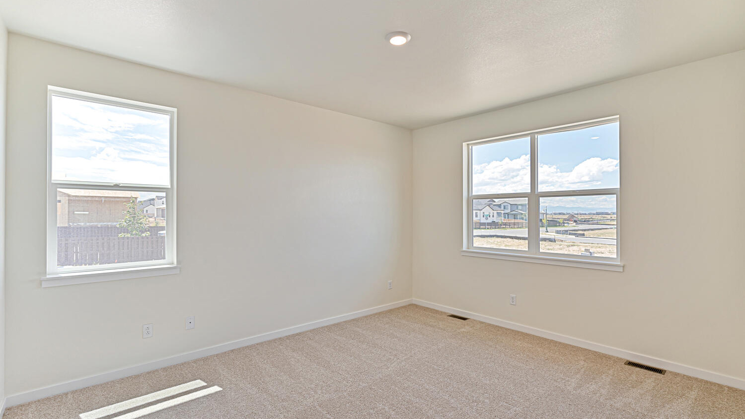 Primary bedroom with two windows for ample natural light, energy efficient LED lighting, and plush carpeting