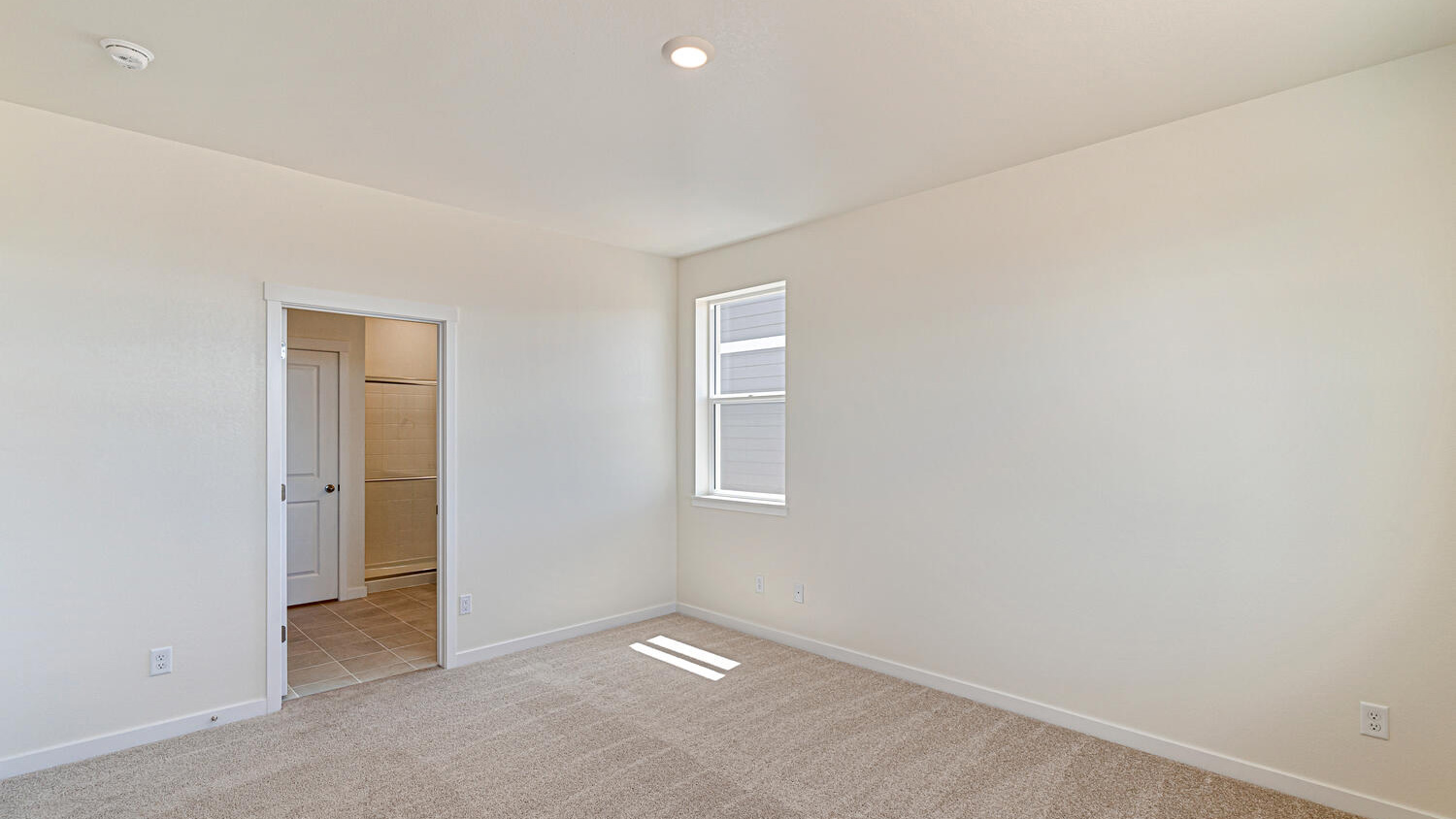 View of corner window and opening to private bathroom in primary bedroom suite
