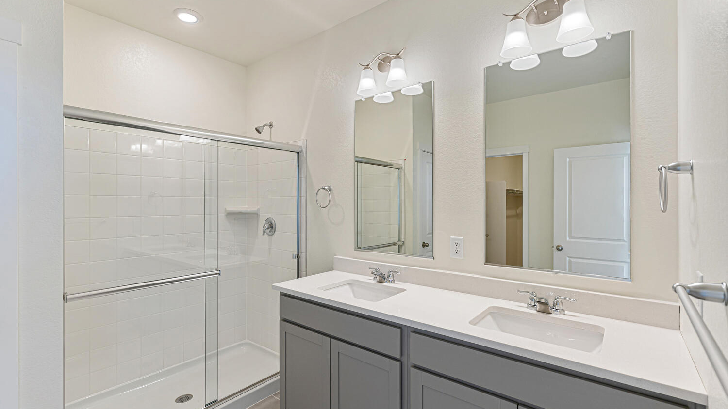Double vanity sinks, chrome fixtures, and large step-in shower in primary bedroom private bath