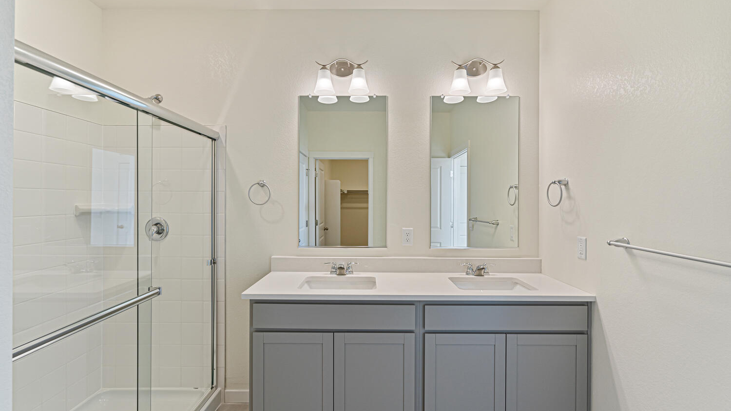 Another view of private bathroom in primary bedroom suite with step-in shower and double vanity sinks