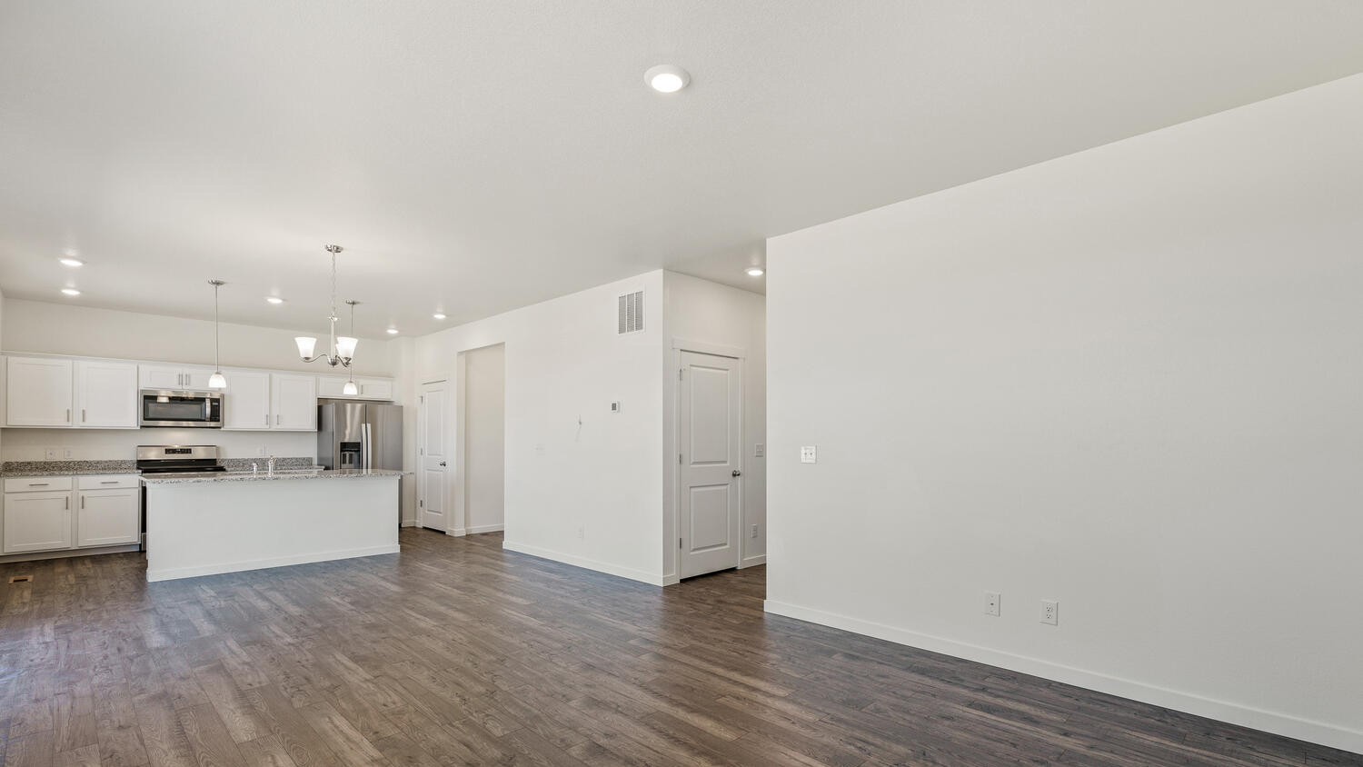 Alternate view of great room, dining nook, and kitchen showing opening to hallway and niche near garage entrance