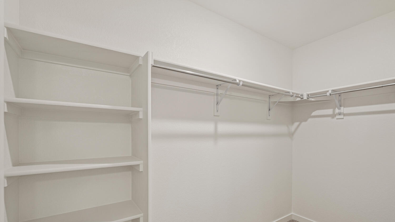 Spacious walk-in closet in primary bedroom suite with built-in shelving and linen storage